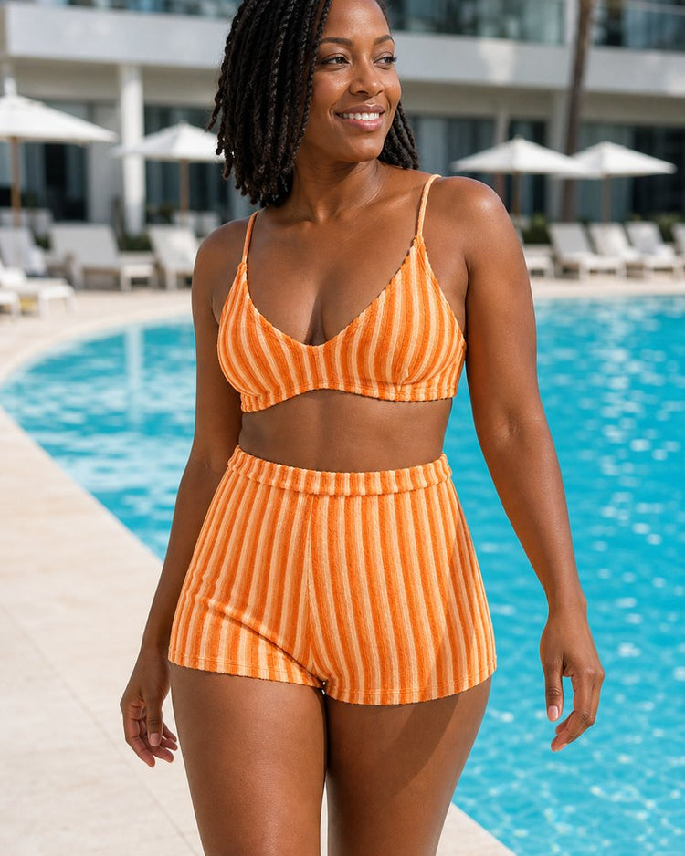Model wearing the Coast Tempo Sunset Stripe Three-Piece Set at modern pool terrace with ocean horizon